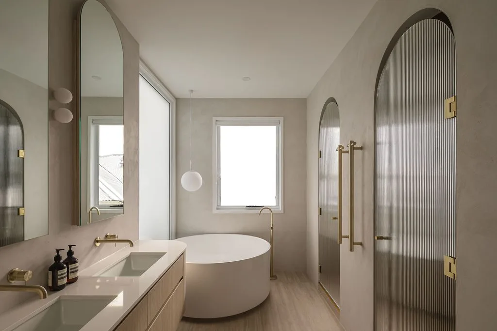 Bathroom with a round freestanding bath, arched mirrors and a reeded glass door, Alto House