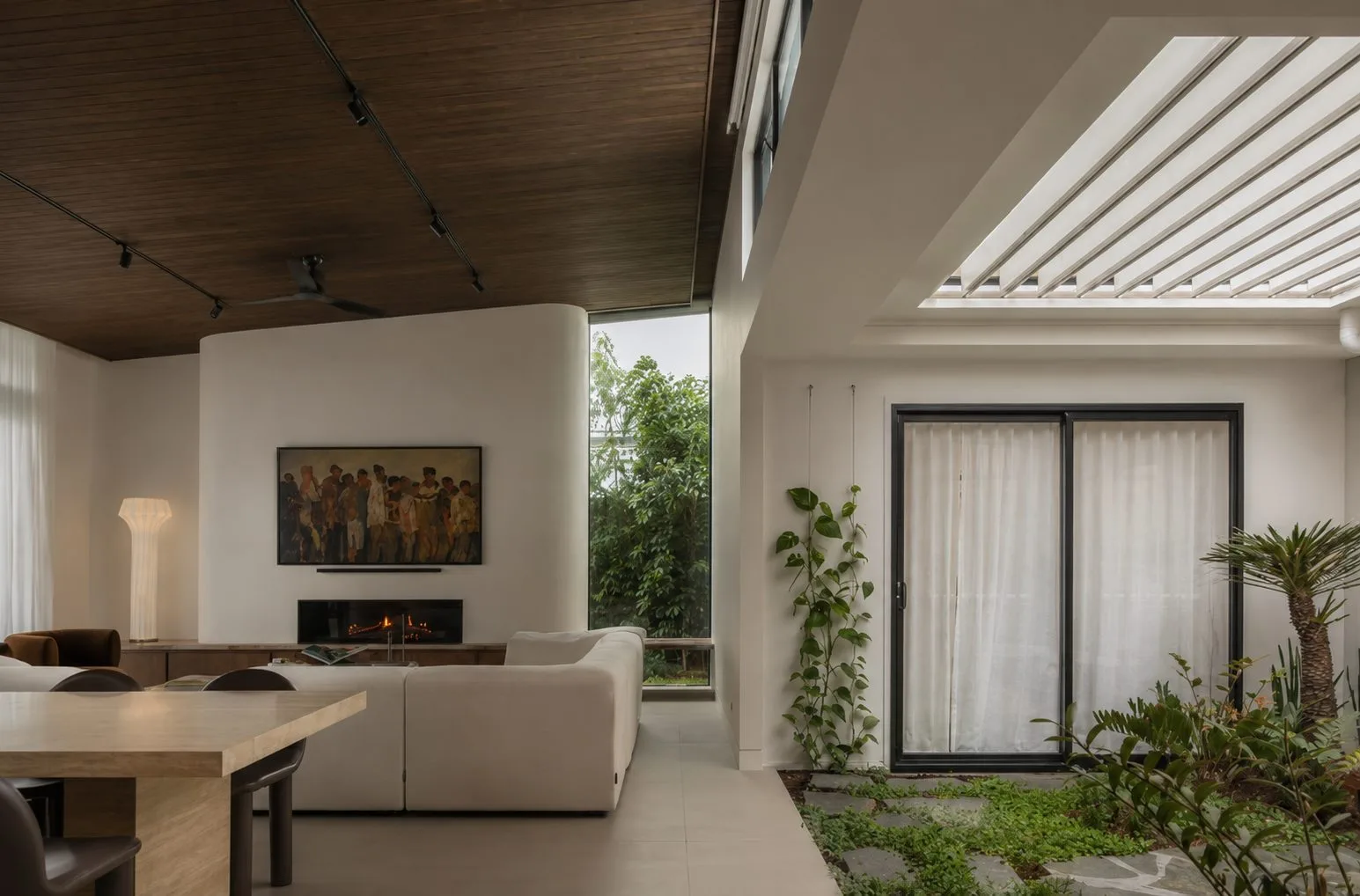 Living room under a timber ceiling, opening to a planted courtyard, Kin House