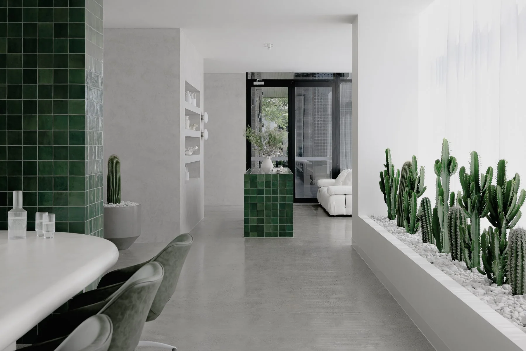 Salon with a green tiled column and a row of cacti, Soja Studios